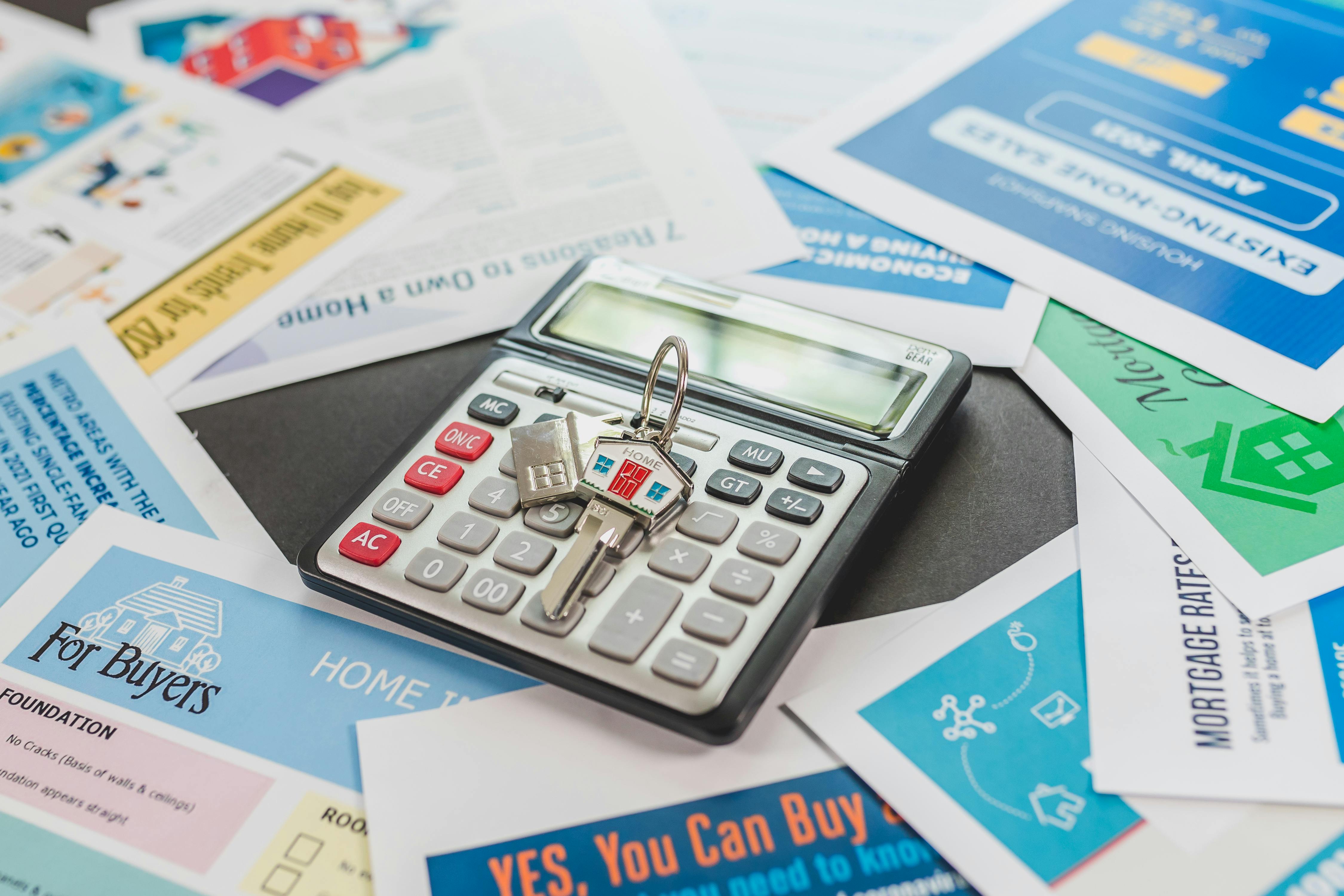 A calculator and housing cost sheets on a desk, representing payment-first home affordability planning.