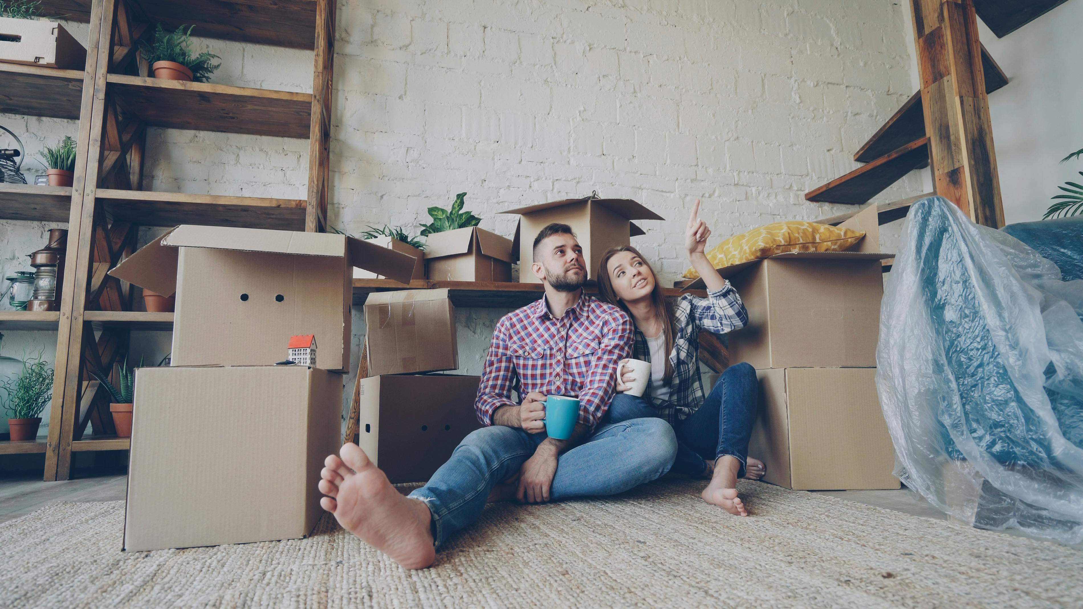 A couple sitting with moving boxes in a new home, representing the gap between qualification and comfortable ownership.