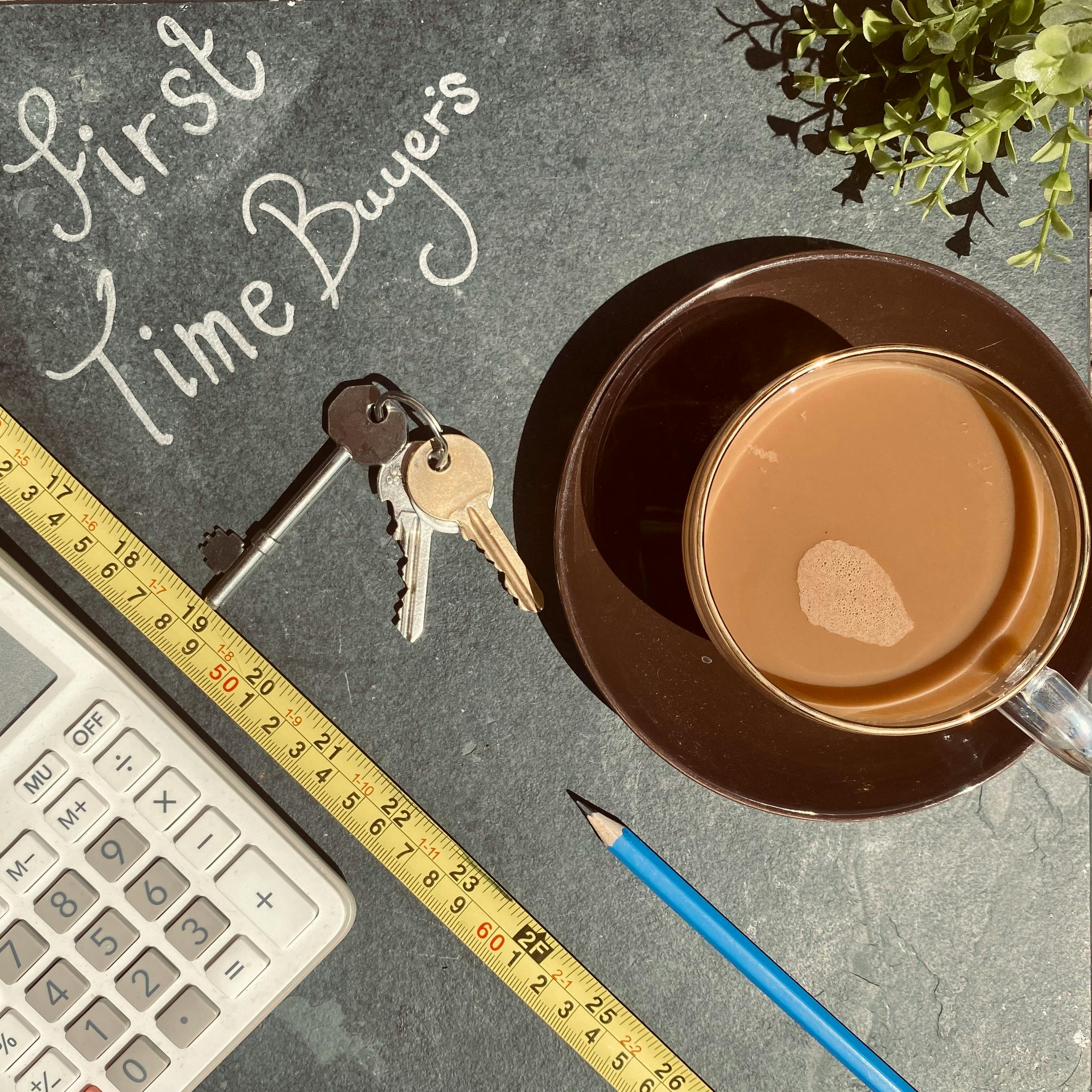 House keys, a calculator, and coffee on a table, representing a home purchase that still needs reserve cash after closing.